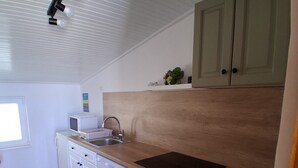 A kitchen with white cabinets, a wooden countertop, a sink, and a window. - Panoramic sea view apartment in Rab (Palit)