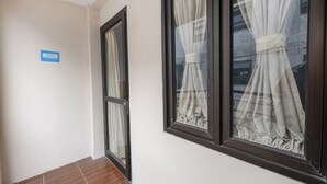 Un corridoio con due finestre, un cartello appeso al muro e un pavimento piastrellato.