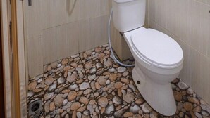 Un bagno con doccia, WC e rivestimenti in piastrelle.
