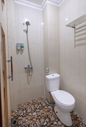Et badeværelse med brusebad, toilet og flisebeklædte vægge.