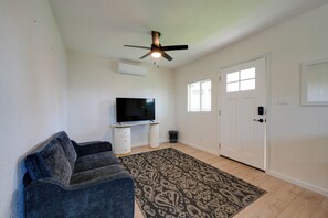 A living room with a ceiling fan, a flat-screen TV on a stand, a patterned rug, a couch, and a door with windows. - Couple’s Escape! 3 Mi to Dtwn & Roosevelt Row (Phoenix)