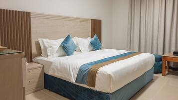 Una cama bien hecha con cabecera de madera, una mesita de noche y una ventana con cortinas.