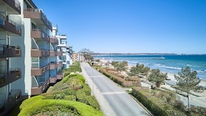 A multi-story residential building with balconies, a road leading to the beach, and a clear view of the ocean. - LichtSpiel Scharbeutz - Arrive, take a deep breath, enjoy - Apartment LichtSpiel (Scharbeutz)