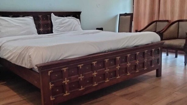 Un lit avec un cadre en bois et des tiroirs, une table de chevet, une chaise et un rideau.