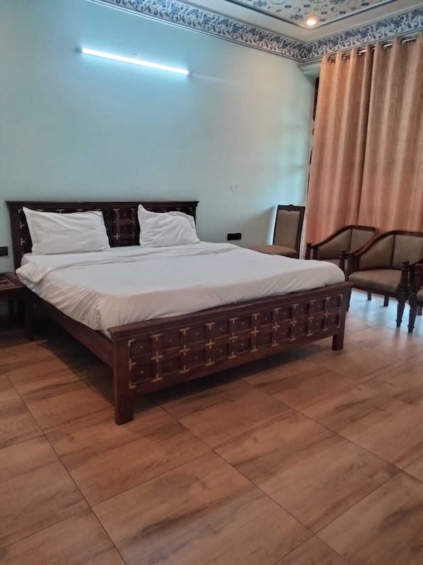 A bedroom with a wooden bed, a nightstand, a chair, and a ceiling light.