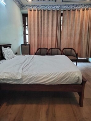 A bedroom with a large bed, two bedside tables, and three chairs.