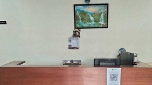 Un comptoir d’accueil agrémenté d’un panneau décoratif, d’un tableau encadré représentant une cascade et d’une petite horloge murale.