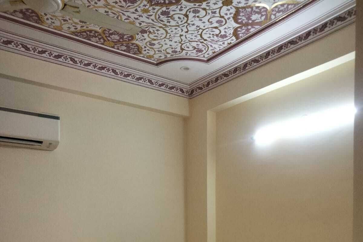 A bedroom with a bed, a ceiling with floral patterns, and an air conditioning unit.