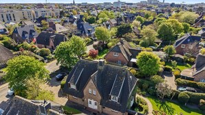 A residential area with houses, trees, and a clear sky. - Stadum Hüs - Charming vacation home for four people with its own garden in (Westerland)