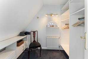 A walk-in closet with a radiator, a chair, and a shelf unit. - Stadum Hüs - Charming vacation home for four people with its own garden in (Westerland)