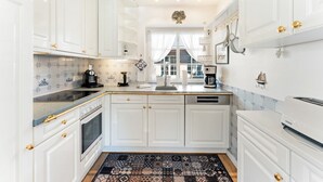 A kitchen with white cabinets, a patterned rug, and a coffee machine. - Stadum Hüs - Charming vacation home for four people with its own garden in (Westerland)