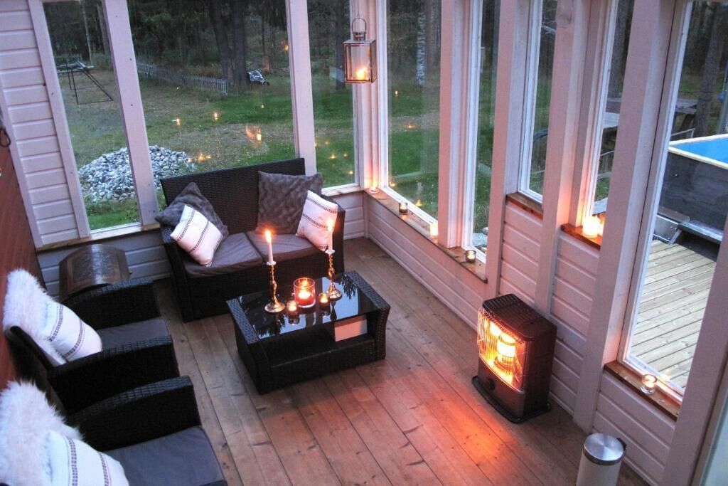 Une pièce chaleureuse avec un canapé, des fauteuils, une table décorée de bougies et un radiateur.