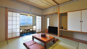 A traditional Japanese room with tatami flooring, a television, and a view of the sea. - Livemax Resort Shikabe (Shikabe)