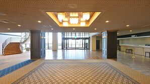 A spacious lobby with a patterned carpet, a staircase, and a reception desk. - Livemax Resort Shikabe (Shikabe)