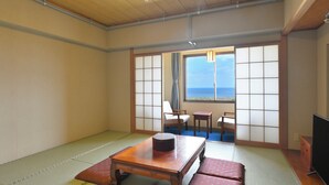 A traditional Japanese room with tatami flooring, a low table, two cushions, and a television. - Livemax Resort Shikabe (Shikabe)