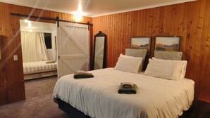A bedroom with a large bed, a sliding door, a mirror, and two framed pictures on the wall.