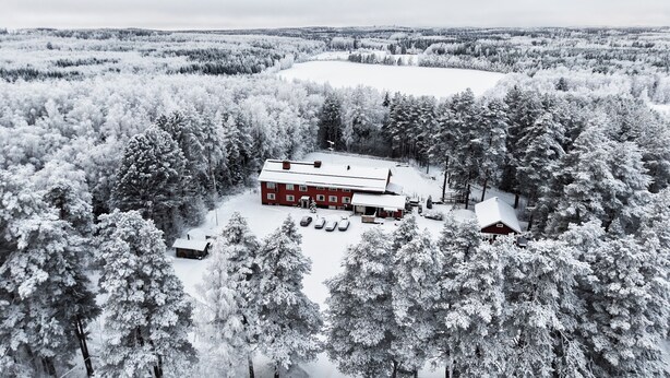 A red building surrounded by snow-covered trees, with a clear view of the surrounding forest. - Old School Lodge Tahko Onnela (Kuopio)