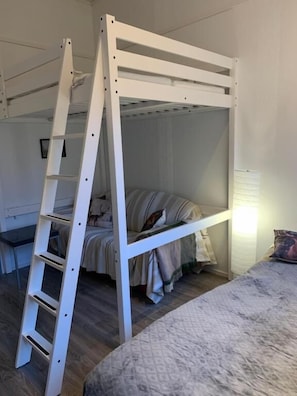 Una cama litera con escalera, una mesita de noche y una lámpara.