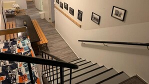 A staircase with a handrail, a wooden bench, and a wall with framed pictures. - Old School Lodge Tahko Onnela (Kuopio)