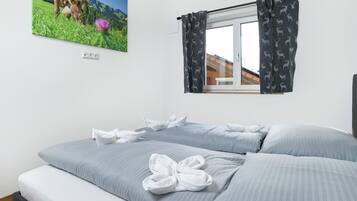 Ein Schlafzimmer mit einem Bett, Kissen, einem Fenster mit Vorhängen und einem Wandbild.