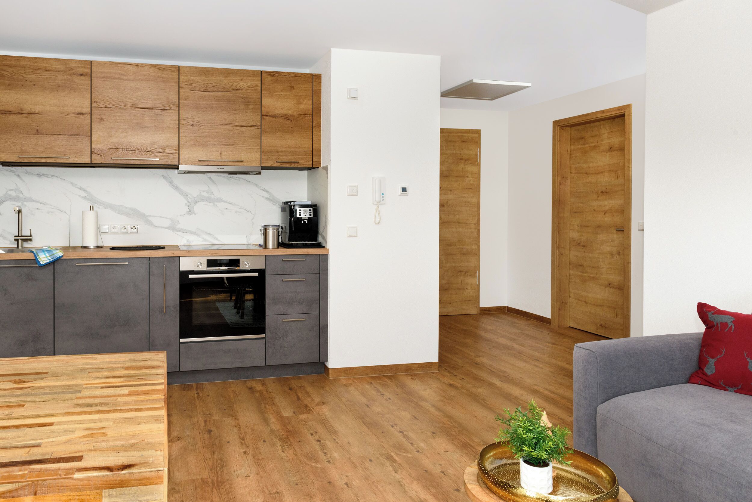 Una cocina moderna con armarios de madera, horno empotrado y cafetera.