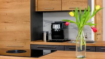 A modern kitchen with wooden cabinets, a coffee maker, and a vase with flowers on the counter.