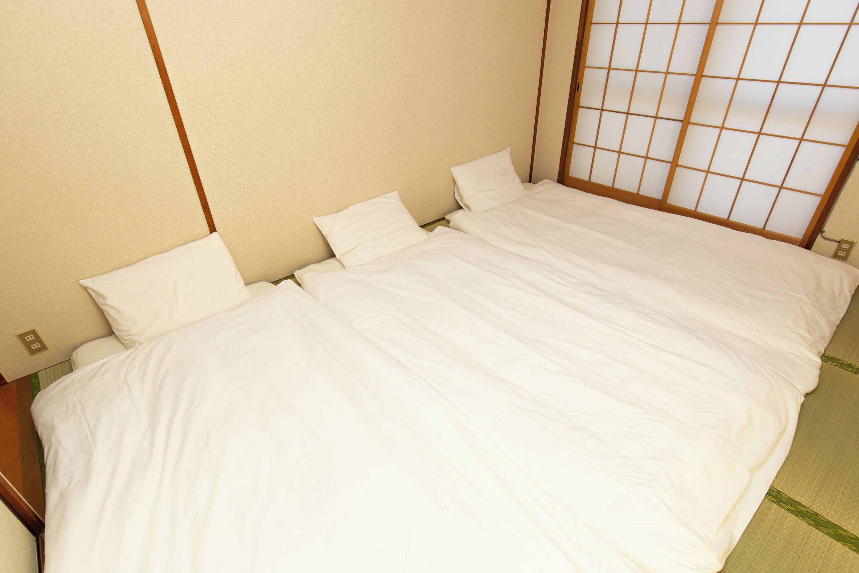 A single bed with white bedding in a room with a traditional Japanese shoji screen door.