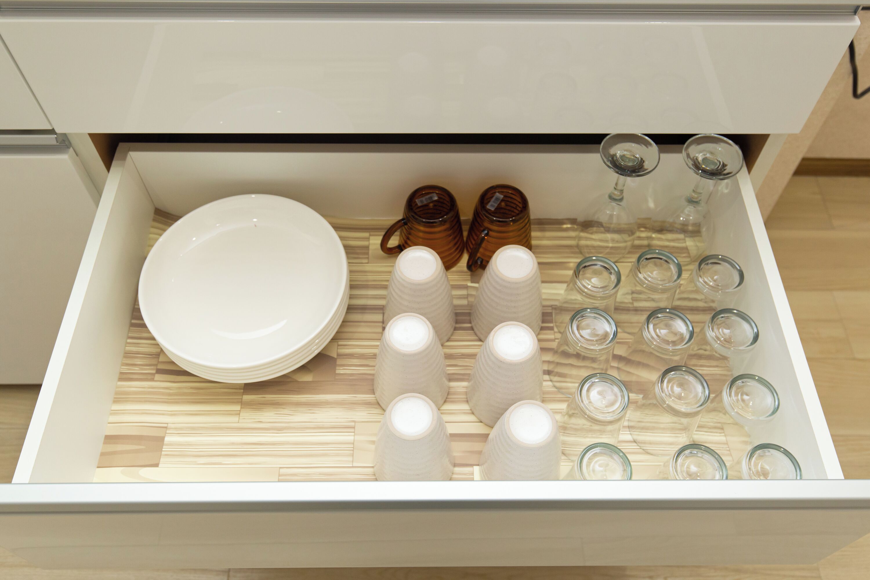 A drawer with neatly arranged plates, cups, and glasses.