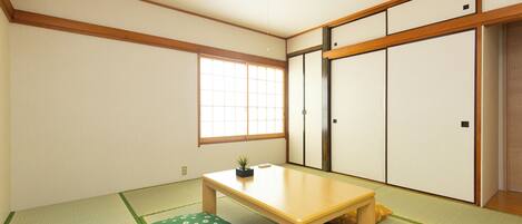 Una tradizionale stanza giapponese con pavimento in tatami, un tavolino in legno, una finestra con pannelli shoji e porte scorrevoli.