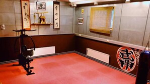 Sala de treinamento de artes marciais com tatames, um saco de pancadas e arte japonesa tradicional.