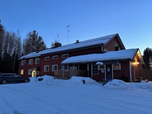 Un bĂątiment rouge avec de nombreuses fenĂȘtres, un toit recouvert de neige et une enseigne indiquant un espace dâaccueil.