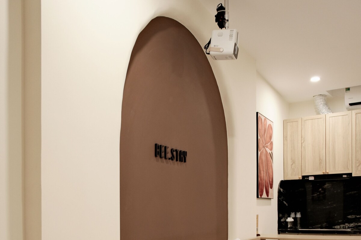 Una habitación de hotel moderna con cama, mesita de noche y una pequeña área de kitchenette.