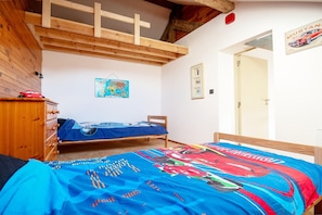 Une chambre à coucher avec un lit, une commode, une carte accrochée au mur et une porte.