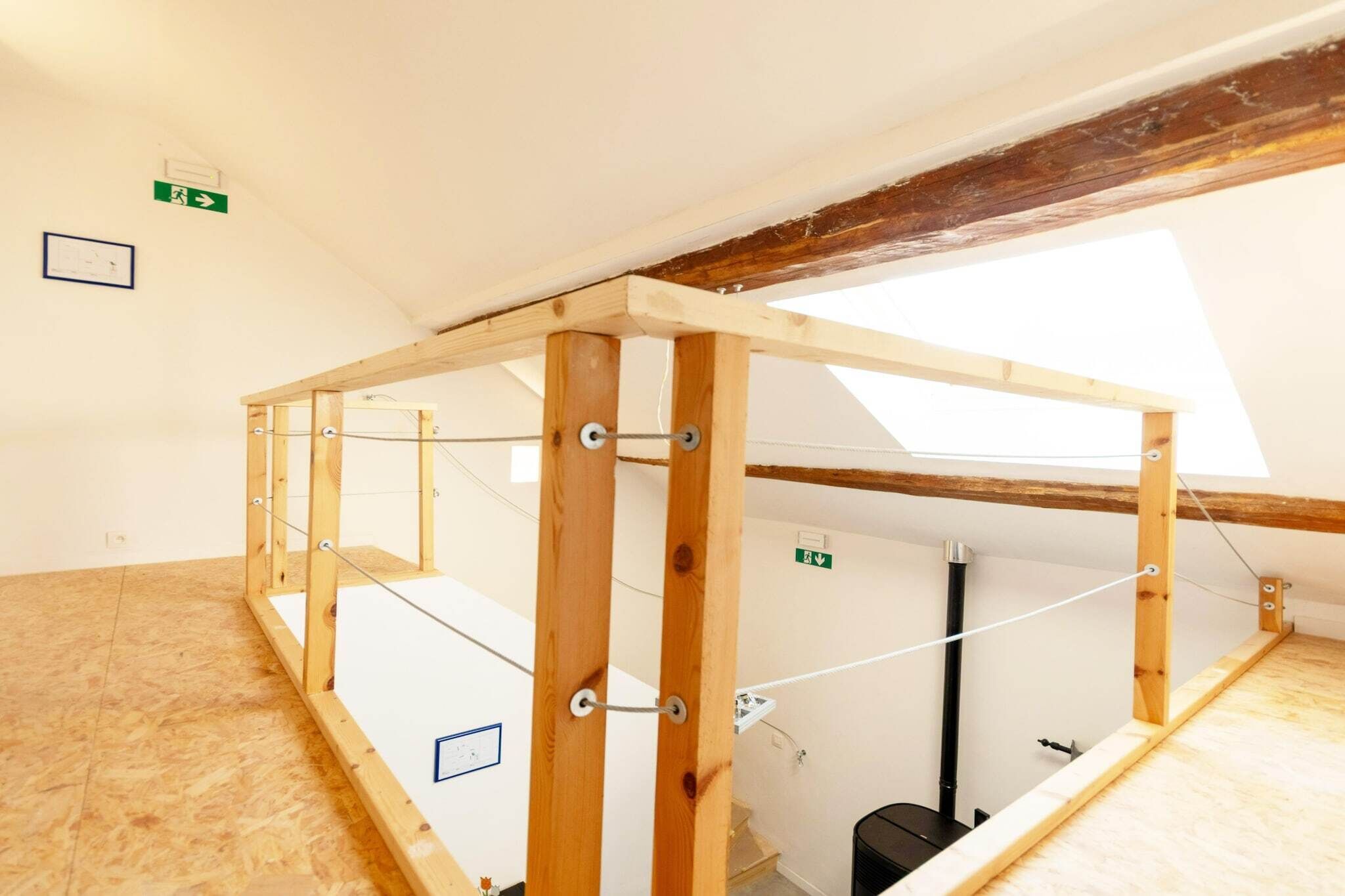 A room with a wooden structure, possibly a loft or attic space, with a skylight and a visible black pipe.