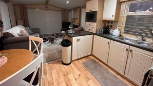 Ein kompaktes Wohnmobil-Interieur mit Küchenzeile, Essbereich und Wohnraum inklusive Sofa und Fernseher.