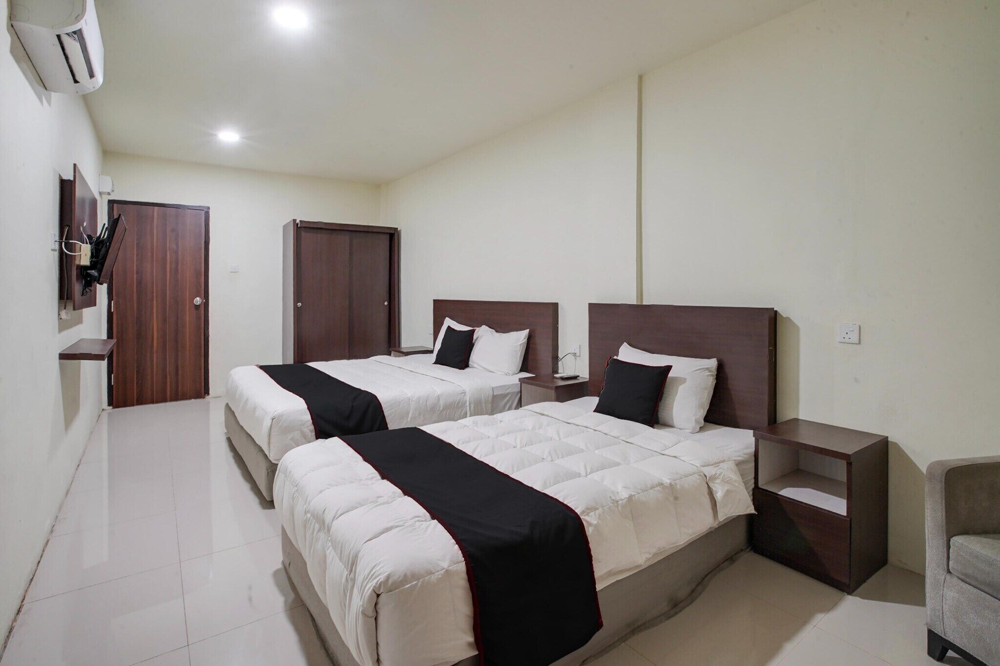 Une chambre d’hôtel avec deux lits, une table de chevet, une chaise et une armoire.