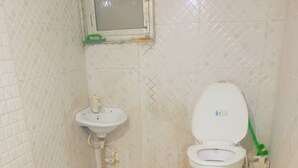 A small bathroom with a toilet, sink, and a window. - Vrindavan Bunk Hostel by Shiva - 5min Walk from Prem Mandir (Vrindavan)