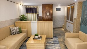 A modern living room with a sofa, coffee table, and a small plant. - Vrindavan Bunk Hostel by Shiva - 5min Walk from Prem Mandir (Vrindavan)