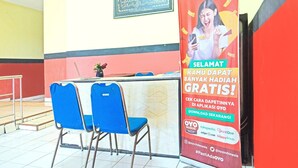 A hotel reception area with a counter, blue chairs, and a promotional poster. - Cozy Twin Escape in Indonesia with Free WiFi (Bandar Lampung)