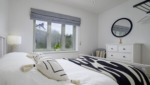 Een slaapkamer met een groot bed, een raam met uitzicht, een dressoir en een spiegel.