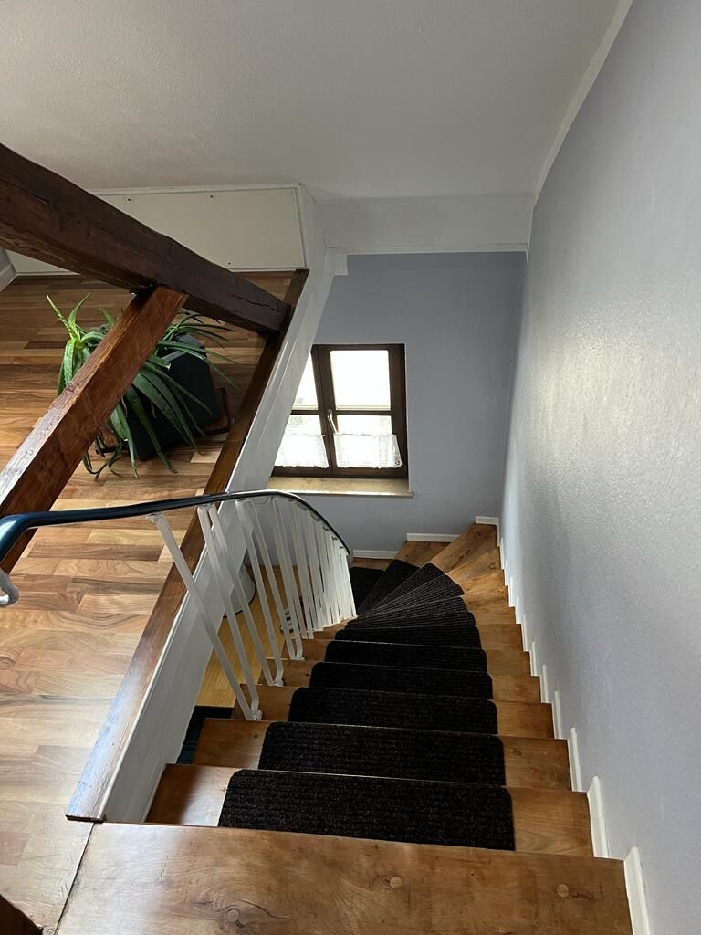 Eine Holztreppe mit weißen Geländern und einem Teppichbelag auf dem Podest.