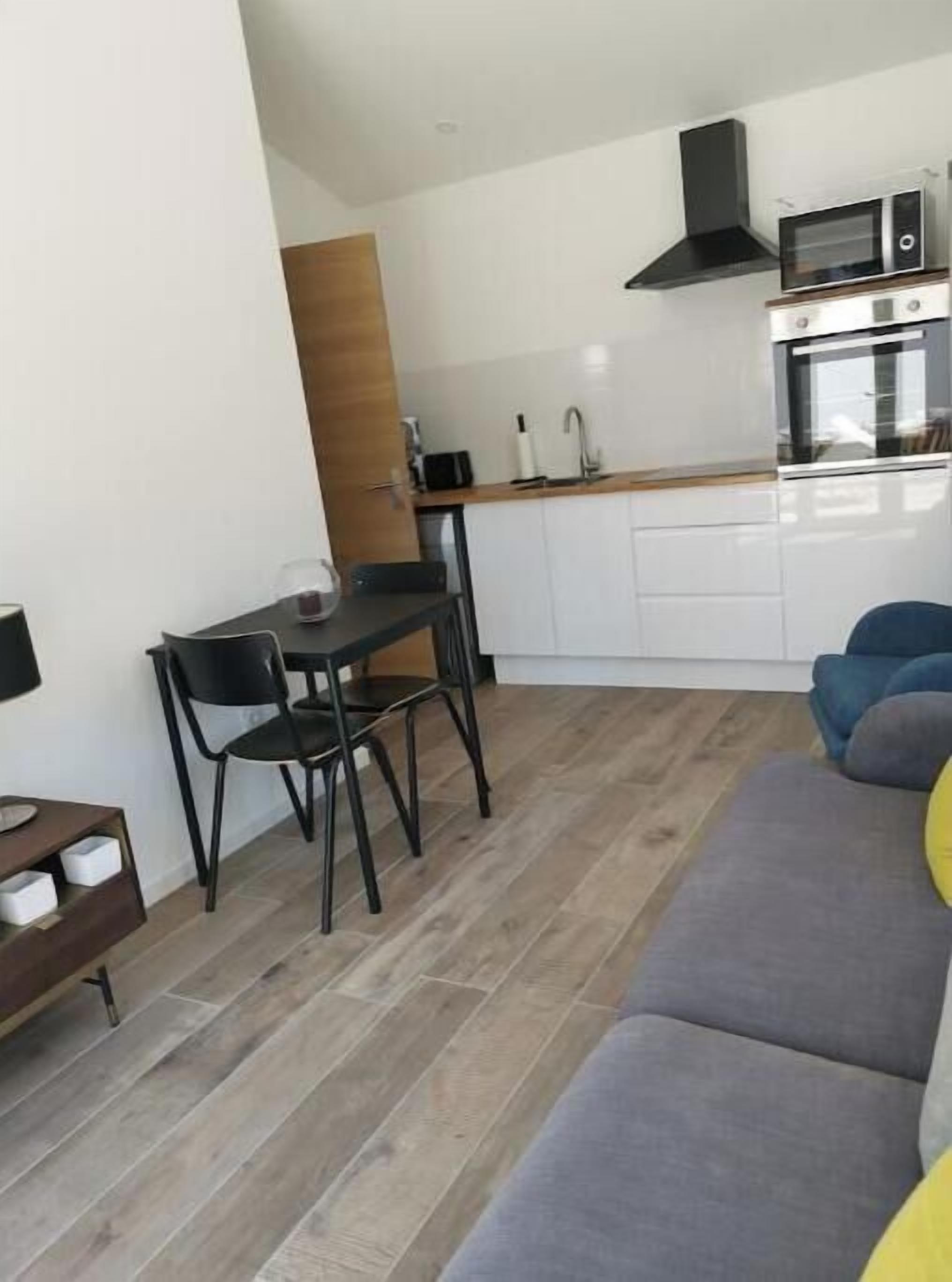 A compact living space with a kitchenette, a dining area with a table and chairs, and a sofa.