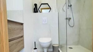 Un baño moderno con ducha, inodoro y tocador de madera.