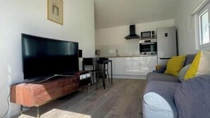 Un espacio habitable compacto con sofá, televisión, comedor y kitchenette.