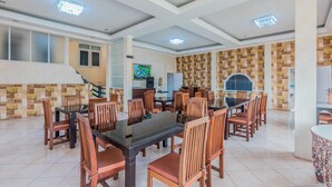 Un comedor amplio con varias mesas y sillas, una escalera y una zona de cocina.