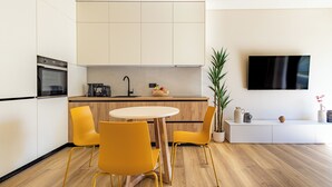 A modern kitchen with a dining area, a flat-screen TV, and a potted plant. - Mandarin One Bedroom Apartment is a short walk from the beach & the town center (Vari)