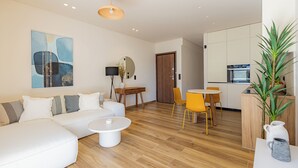 A modern living room with a sofa, coffee table, and dining area with chairs. - Mandarin One Bedroom Apartment is a short walk from the beach & the town center (Vari)