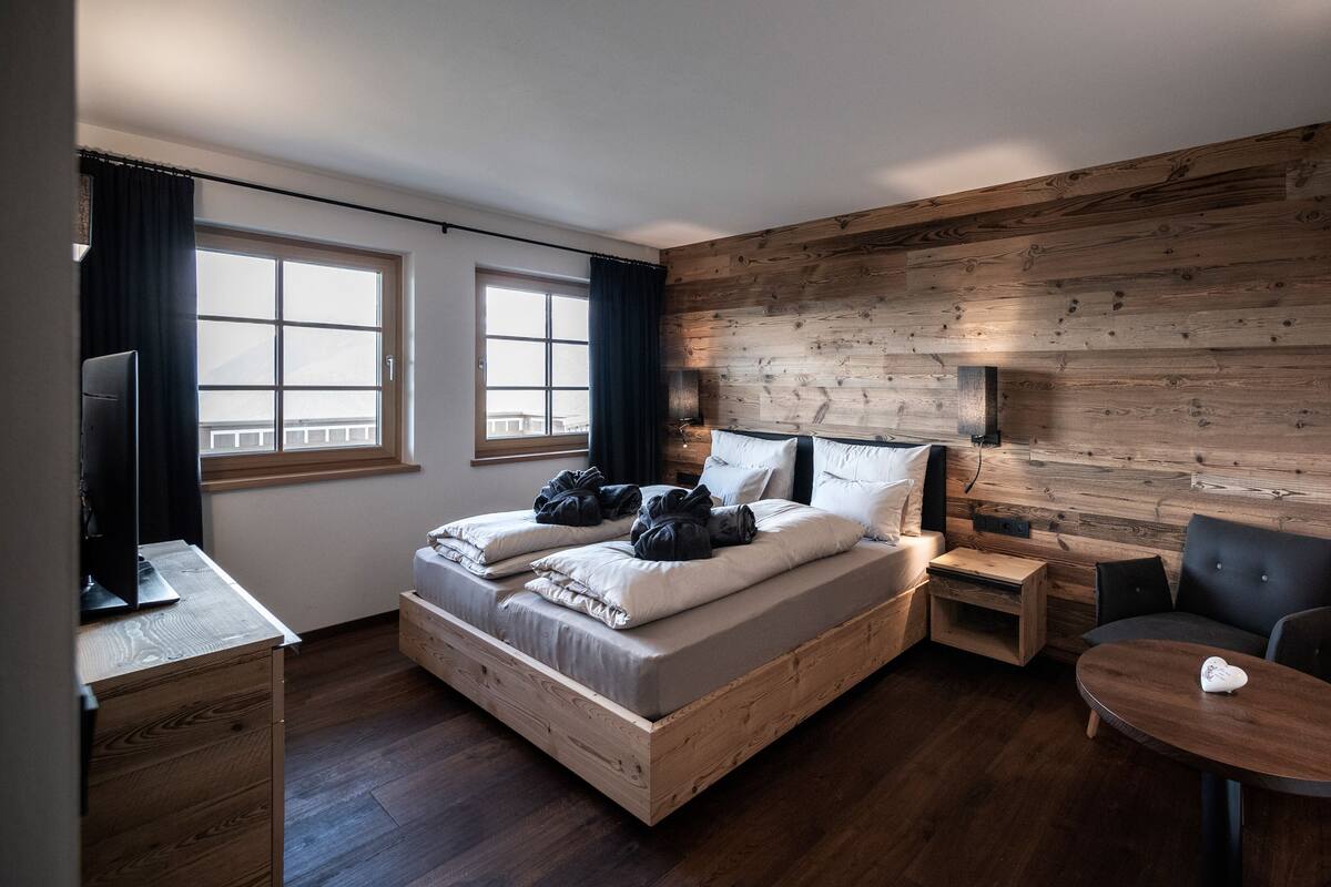 A room with a wooden bed, a desk, a chair, and a small table.