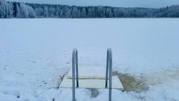 A snowy landscape with a frozen lake and a metal structure in the foreground.