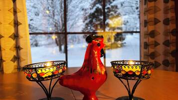 A red ceramic rooster between two candle holders on a table.